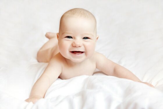 Smiling baby on white sheets