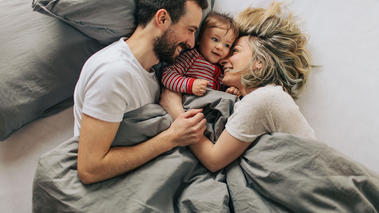 Happy family smiling at each other in bed