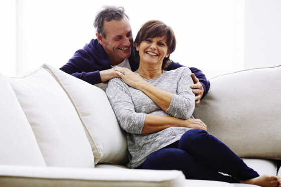 Mature couple holding hands and laughing on the couch