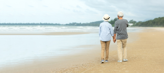 Senior couple walking on the beach holding hands