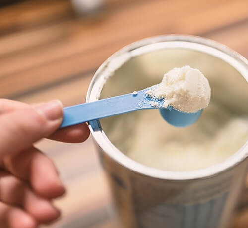 Image of baby formula being scooped out of a tin