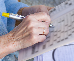 A person completing a crossword in the newspaper